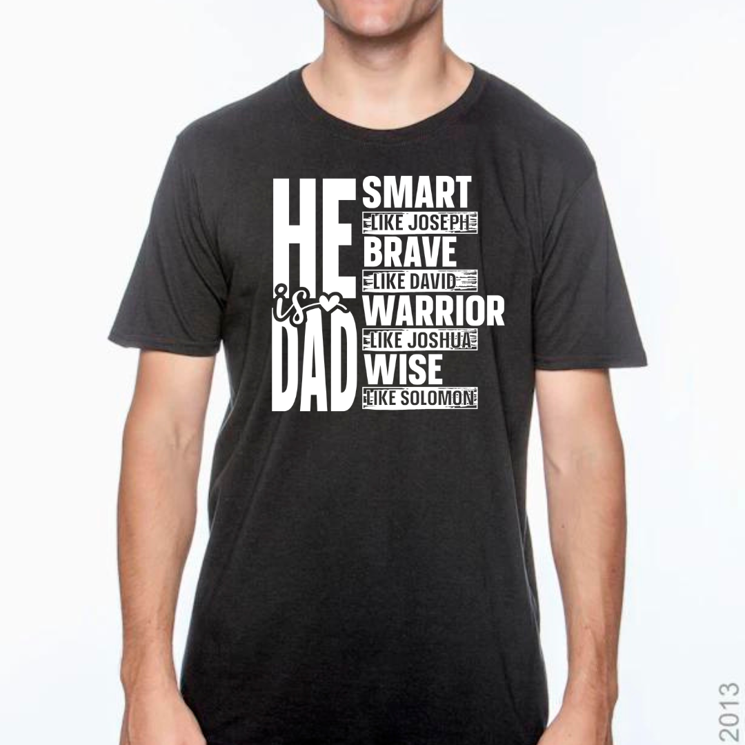 Image of a white T-shirt with the phrase ‘He Is Dad’ in bold, modern typography. Below the main text, the shirt features inspirational attributes linked to biblical figures: ‘Smart like Joseph,’ ‘Brave like David,’ ‘Warrior like Joshua,’ and ‘Wise like Solomon,’ each line styled to highlight these venerable qualities. The design is also available in red, black, and gray color options, visible in smaller images positioned beside the main white T-shirt.