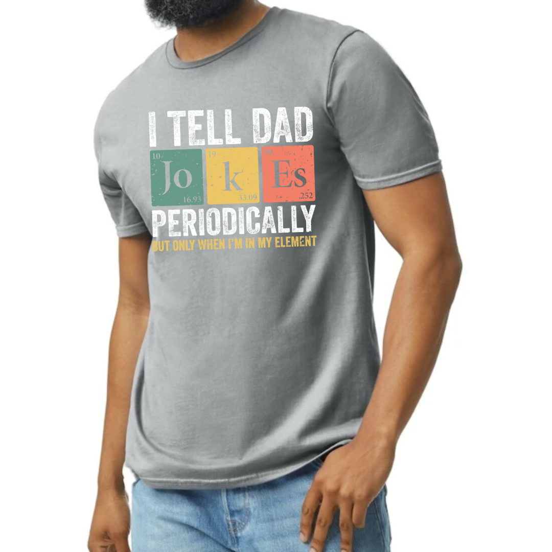 Image of a T-shirt available in black or gray, featuring a witty design that mimics the periodic table titled ‘I Tell Dad Jokes Periodically.’ Each ‘element’ on the table cleverly incorporates a classic dad joke, blending humor with a touch of scientific charm. This playful and educational design makes it a perfect gift for dads who love to share laughs and knowledge in equal measure.