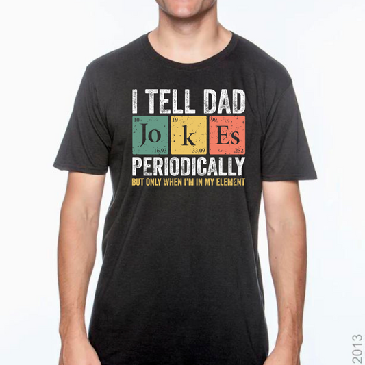 Image of a T-shirt available in black or gray, featuring a witty design that mimics the periodic table titled ‘I Tell Dad Jokes Periodically.’ Each ‘element’ on the table cleverly incorporates a classic dad joke, blending humor with a touch of scientific charm. This playful and educational design makes it a perfect gift for dads who love to share laughs and knowledge in equal measure.